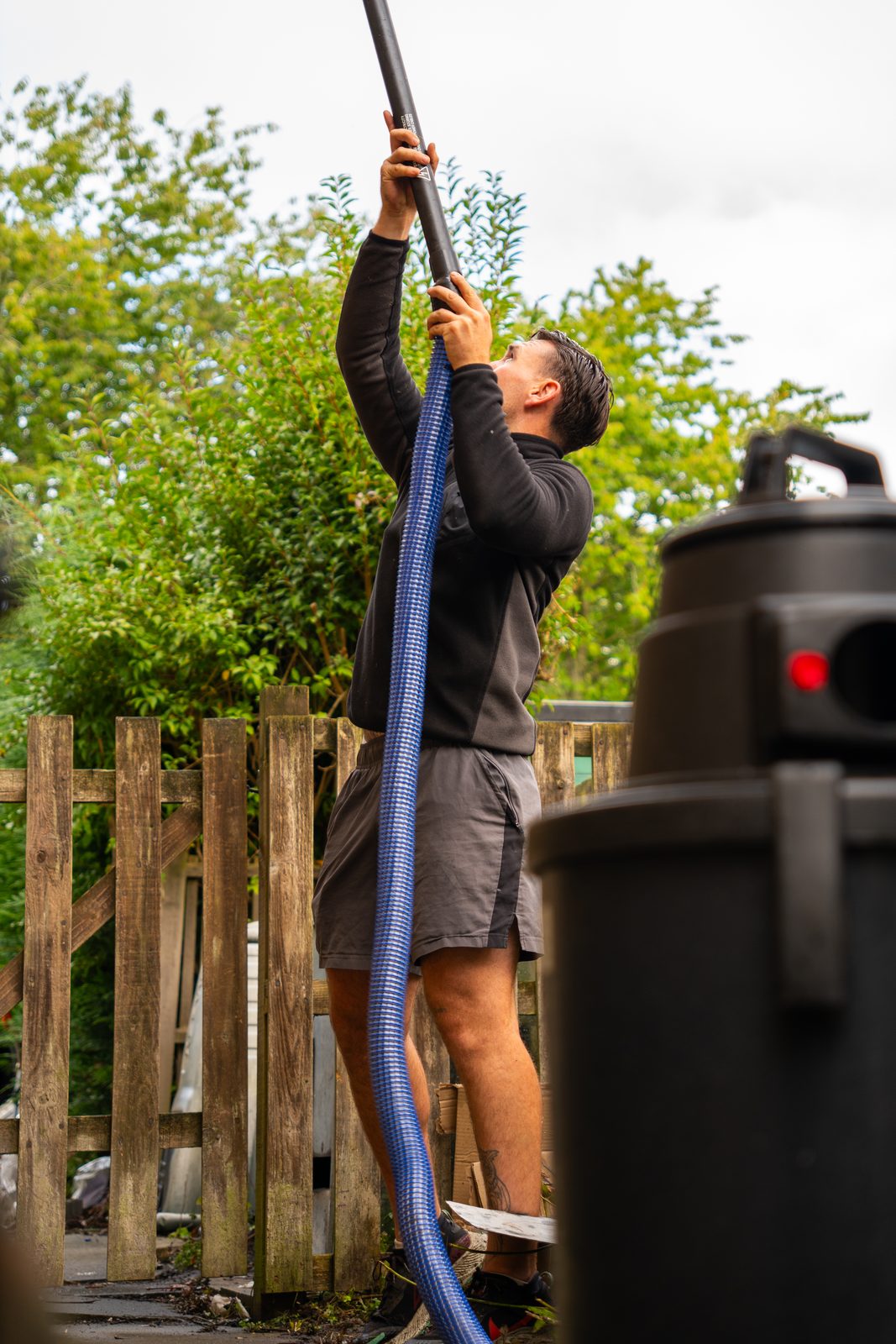 Gutter vacuum pole and hose in use